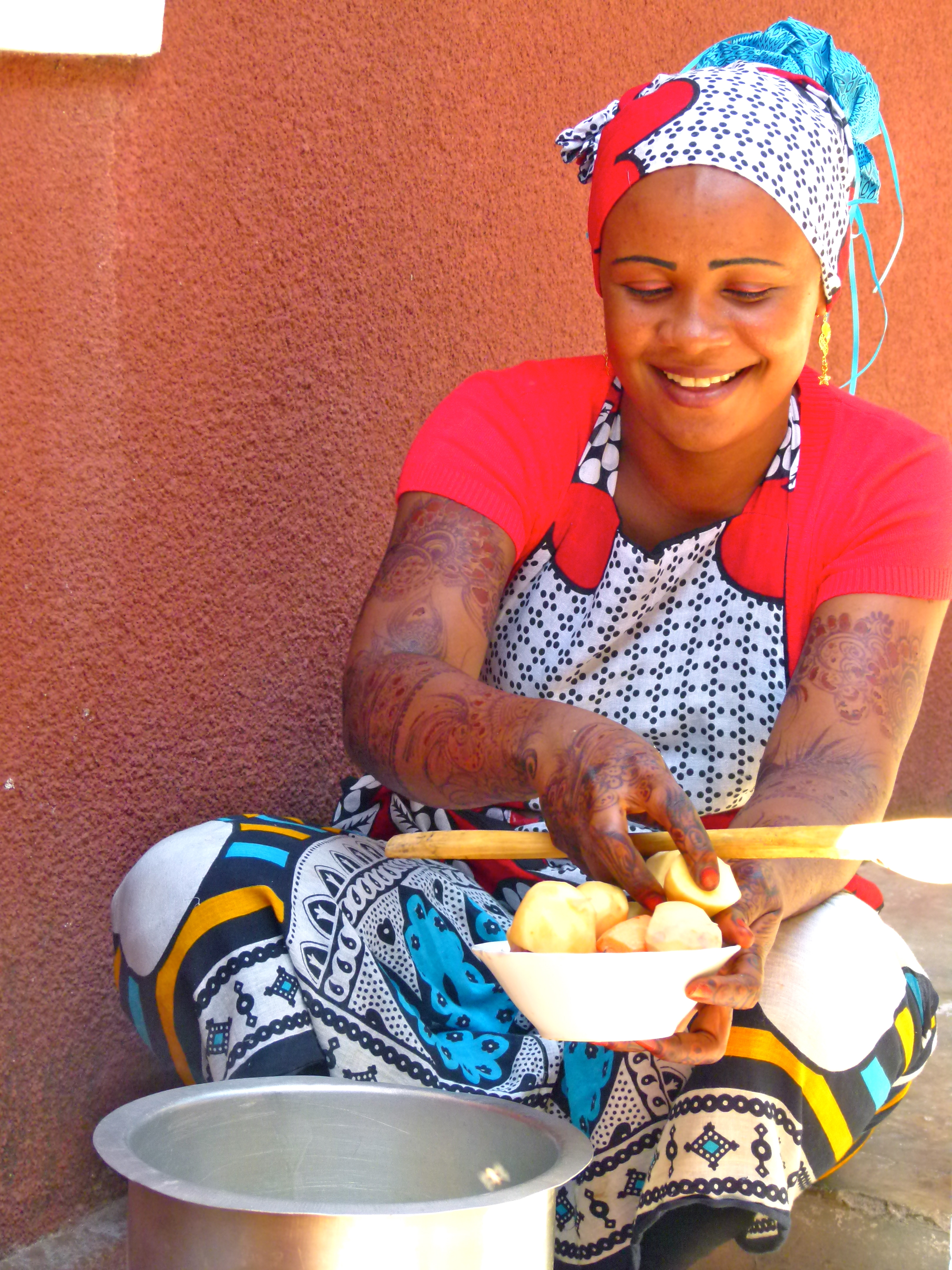 Eine junge Frau mit Henna bemalten Armen kocht in einem Hinterhof