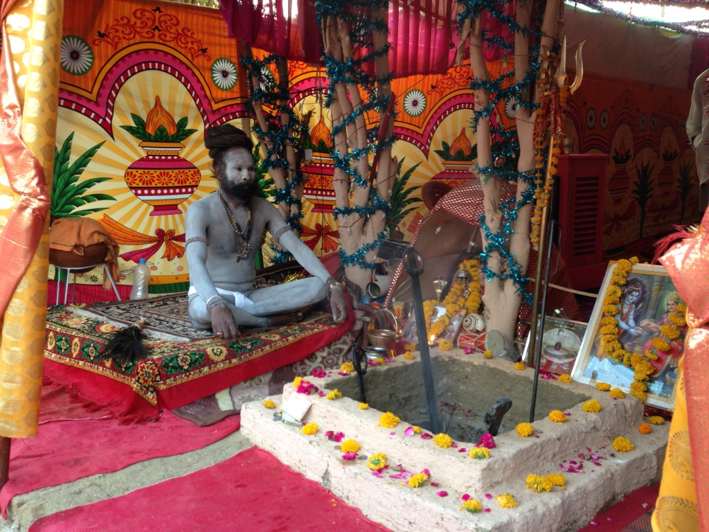 Ein Sadhu meditiert am Morgen vor der Feuerstelle in seinem Zelt